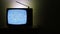 Video of an old television in left side on dark background with no signal and grainy noise effect on the screen
