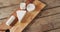 Video overhead shot of assorted soft cheeses on chopping board, on wooden table with copy space