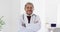 Video portrait of biracial male doctor standing with arms crossed smiling to camera