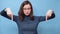 Video portrait of a charming serious girl student with glasses in a blue sweater pointing her hands down