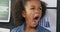 Video portrait of happy, tired biracial schoolgirl yawning in school classroom