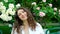 Video portrait of a laughing 35-year-old woman with natural hair against a background of blooming roses in the garden.