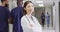 Video portrait of smiling asian female doctor standing in busy hospital corridor, copy space
