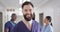 Video portrait of smiling, bearded caucasian male medical worker in busy hospital corridor