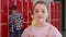 Video portrait of smiling schoolgirl standing in school corridor.