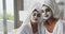 Video of relaxed diverse female friends moisturizing with face masks in bathroom