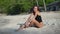 Video of slim tanned brunette in a black swimwear isolated on beach sand, posing for the camera, puts her head on