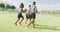 Video of three african american schoolchildren playing football barefoot in field