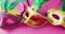 Video of three carnival masquerade masks with green feathers on pink background