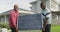 Video of two african american men carrying the solar panel