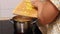 Video of unrecognizable female hands putting, adding yellow potato cubes as ingredient for soup in boiling broth in pan