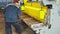 Video. Worker cuts metal rods on mechanical guillotine machine in production hall. slow motion