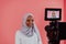 Videographer in digital studio recording video on professional camera by shooting female Muslim woman wearing hijab