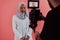 Videographer in digital studio recording video on professional camera by shooting female Muslim woman wearing hijab