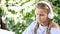 Videoportrait of adorable girl sitting at table with a white notebook, putting headphones on