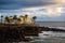 Vie to the ocean and rocky shore with buildings on sunset.