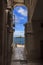 Vieste`s historic center: view of the lighthouse from a arcade on the harbor.It` is located on the islet of Santa Eufemia.