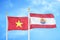 Vietnam and French Polynesia two flags on flagpoles and blue sky