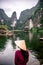 Vietnamese Girl with straw hat in Trang An Scenic Landscape formed by karst towers and plants along the river (UNESCO World