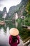 Vietnamese Girl with straw hat in Trang An Scenic Landscape formed by karst towers and plants along the river (UNESCO World