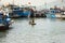 Vietnamese Man Padding Round Woven Bamboo Coracle. Fishermen On Their Boats At The Background