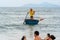 Vietnamese marine lifeguard in a traditional round woven bamboo boat watches people swimming in the permitted area on the city