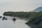 Vietnamese old women on traditional boat paddling by yellow brown water in canal.