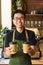 Vietnamese smiling waiter holding paper cups with coffee in a cafe