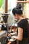 Vietnamese waitress making coffee via portafilter of a coffee machine