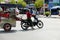 Vietnamese woman ride motorbike pull food cart stop on street