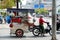 Vietnamese woman ride motorbike pull food cart stop on street