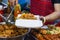 Vietnamese woman serving chicken paws in plastic box with chili in vietnamese night market