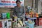 A Vietnamese woman trades on the street and makes juice from a sugar cane with lemon. The sign says: `coconut water, fruit yogurt