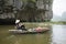 Vietnamese woman in traditional conical hat rows boat into natural cave on Ngo river, Tam Coc, Ninh Binh, Vietnam