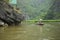 Vietnamese woman in traditional conical hat rows boat into natural cave on Ngo river, Tam Coc, Ninh Binh, Vietnam
