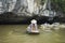 Vietnamese woman in traditional conical hat rows boat into natural cave on Ngo river, Tam Coc, Ninh Binh, Vietnam