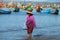 Vietnamese woman walks along the coastal strip of the sea with goods on her head. The fishing harbour of Mui ne, Vietnam