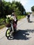 Vietnamese woman wear face mask, glasses, helmet, ride motorbike transport flower pot at noon