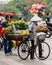 Vietnamese woman wearing asian conical hat sell flowers on her bicycle at street of Hanoi, Vietnam