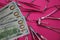 View on 100 us dollar paper bill notes. surgical steel instruments and hyaluronic acid syringe on pink background - cosmetic