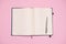 View from above. Blank pages of a notepad and stylish silver pen, isolated on pink background. Copy advertising space