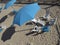 View from above of a blue beach umbrella and set of wooden table and chairs in blue and white.