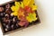 View from above on box from dark wood with chestnuts. Decoration from colorful autumn leaves. White table background with c