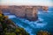 View from above from a cliff of the blue bubbling ocean and orange rocks at dawn. Campbell National Park in Australia