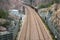 View from above of double railroad tracks in a mountain and forest environment.