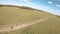 View from above flying fpv drone two bicyclist traveling on bicycle across green field in summer countryside. Tourist