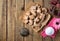 View from above of gingerbread on baking paper, sieve, pink dried flowers and icing sugar on rustic wooden boards