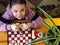 View from above. The girl learns to play table chess and cheerfully looks up at the camera. Board games are an alternative to