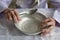 View from above.The hands of an old grandmother of 90 years are holding an empty aluminum bowl and spoon, poverty and poverty, the