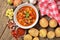 View from above of potato and sausage goulash, pepper, onion and garlic on wooden table and red dish-cloth